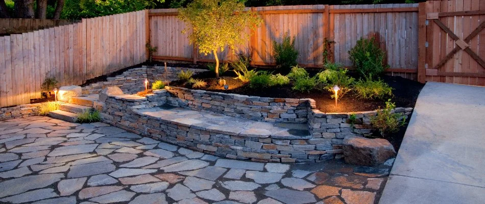Planter bed atop a stone wall in Saddle River, NJ, with lighting.