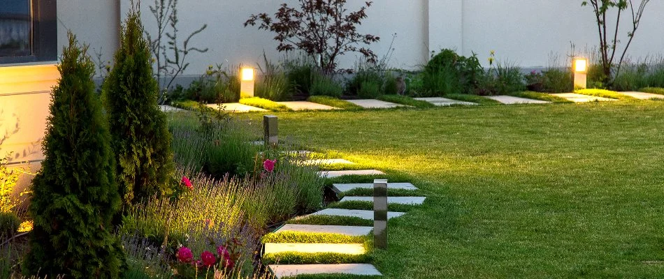 Lawn, landscape, and walkway in Queens, NY, with outdoor lighting.