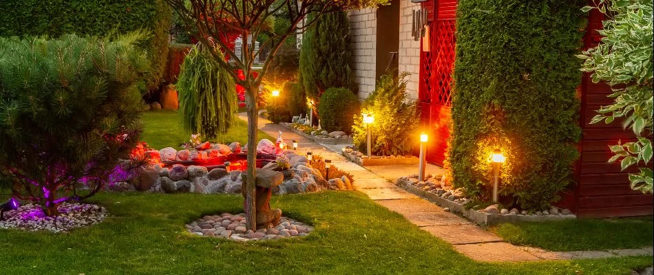 Landscape lighting along a walkway in Brooklyn, NY, beside a lawn with trees and plants.