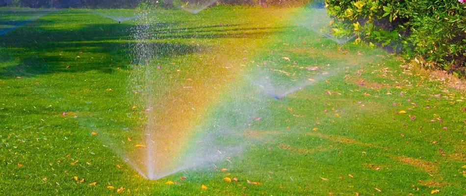 Sprinkler heads releasing water over a green lawn in Orangetown, NY.